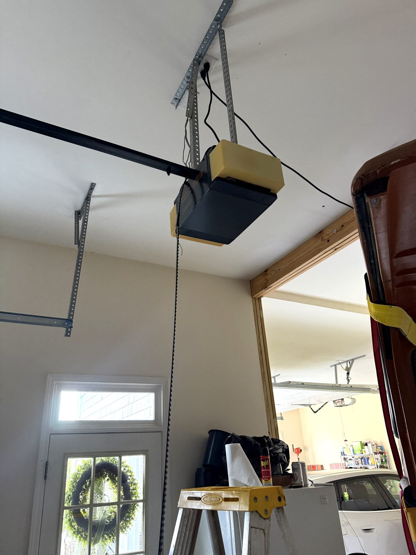Old chain-drive garage door opener mounted on angle iron before replacement in Chamblee, GA